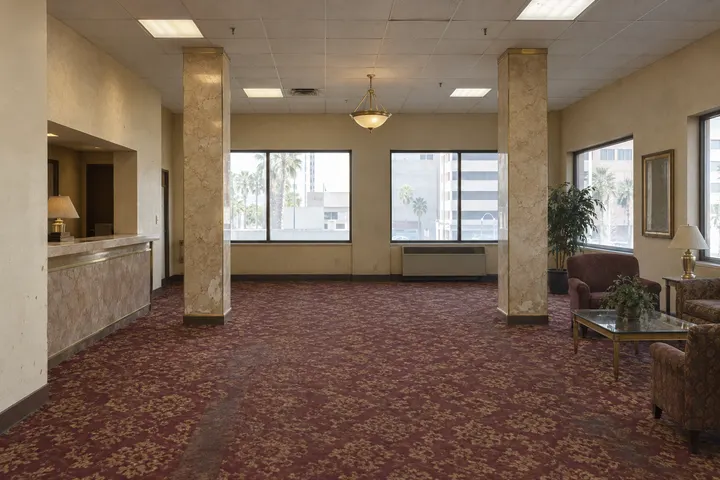 The example lobby as it is: patterned carpet, a dated reception counter and old armchairs
